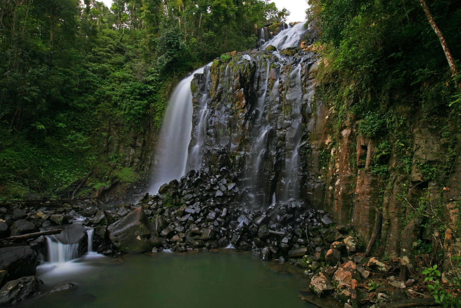 Un primer plano de una cascada en un bosque con un cuerpo de agua (cascada, naturaleza, recursos hídricos, cuerpo de agua, agua)