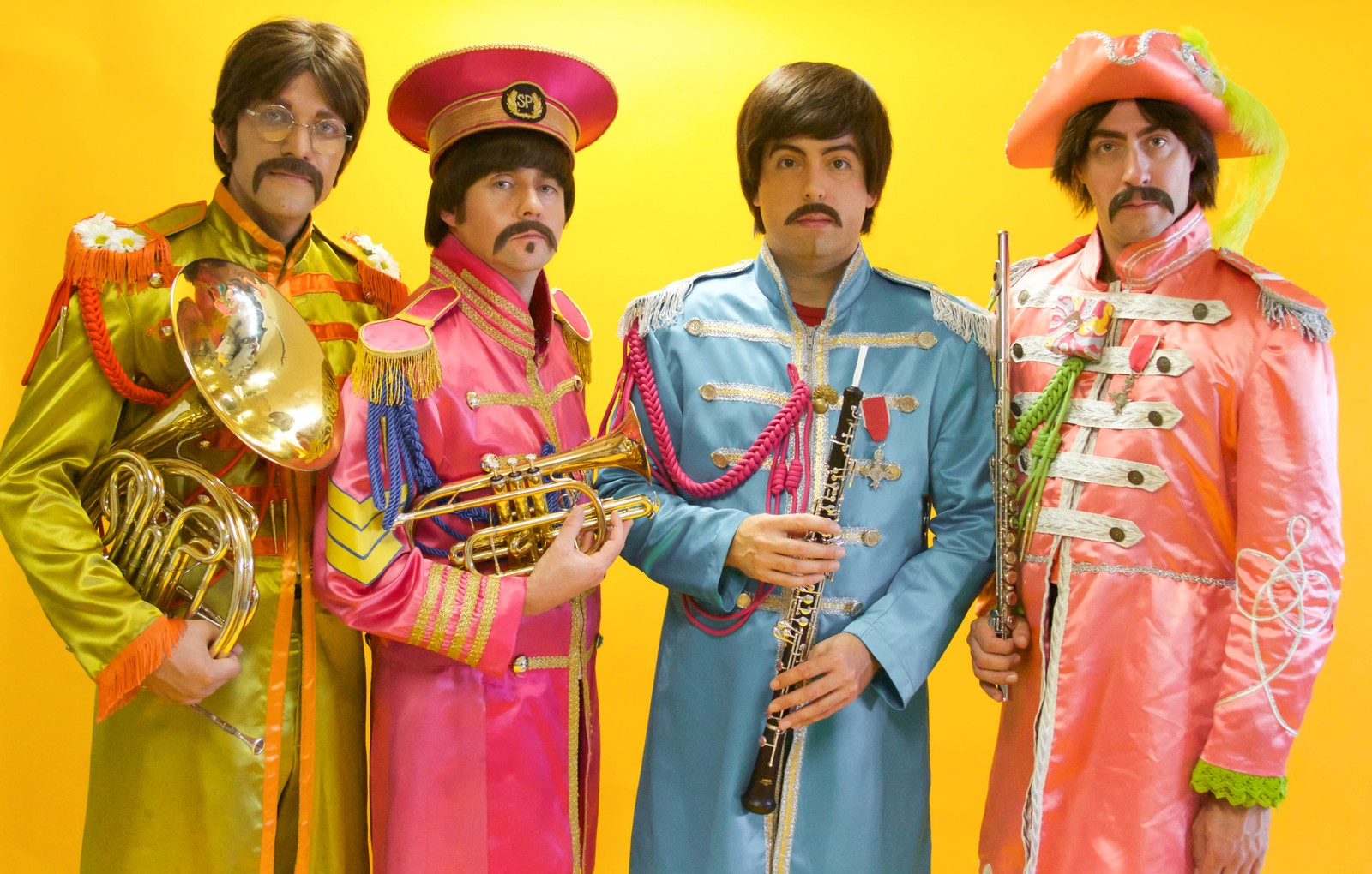 A close up of three men in colorful outfits holding instruments (the beatles, tribute act, musical theatre, event, costume)