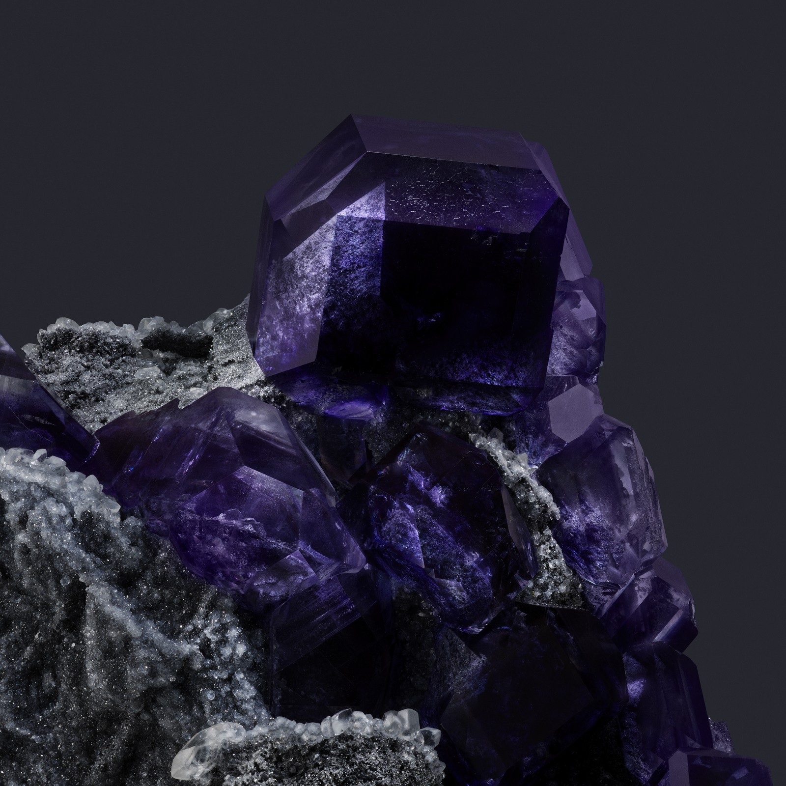 A close up of a purple crystal on a rock with a black background (sapphire, fluorite crystal, fractal, gemstone, google pixel 8 pro)