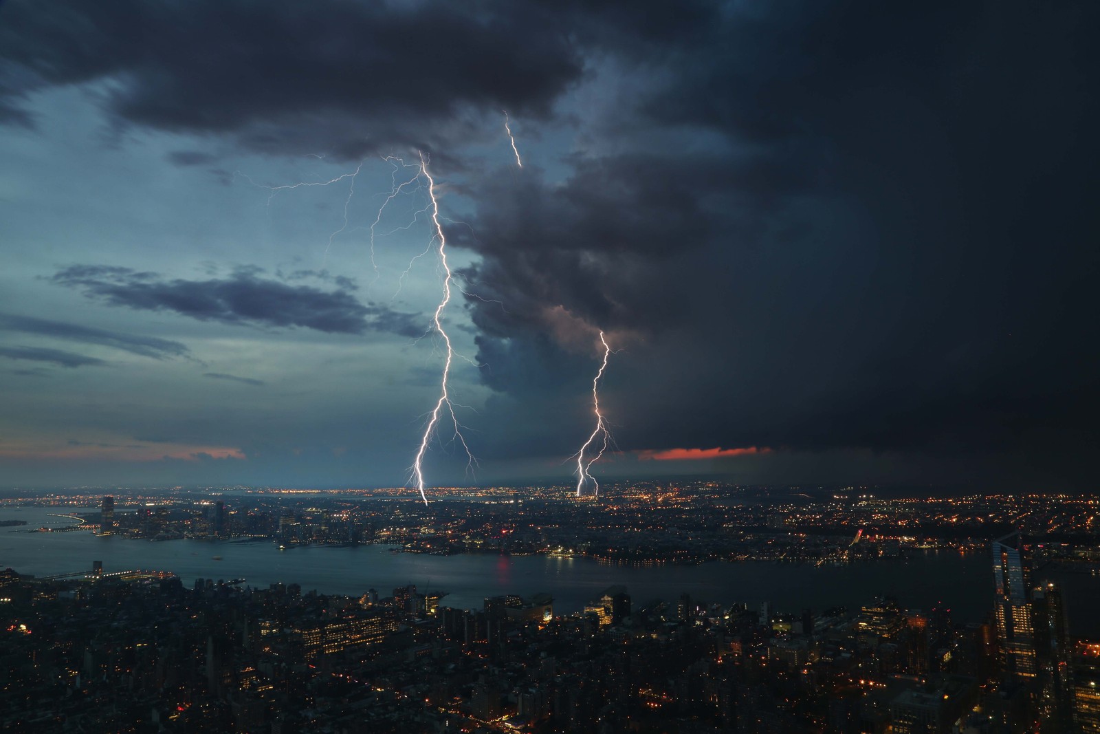 Arafed lightning strikes through the sky over a city at night (lightning, storm)