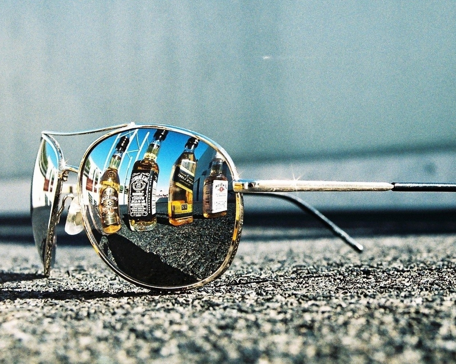 Mirrored image of a pair of sunglasses with a bottle of alcohol in the reflection (black label, jack daneil, johnny walker, whiskey)