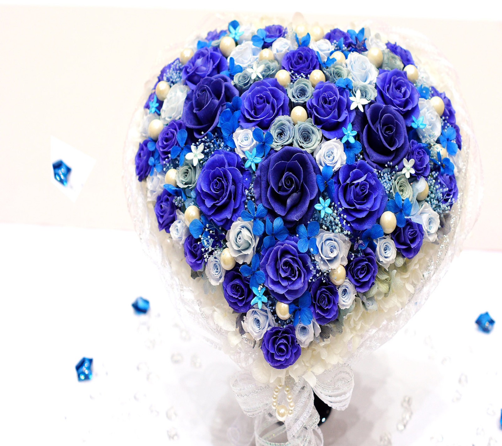 There is a bouquet of blue roses and pearls in a vase (flower, heart)