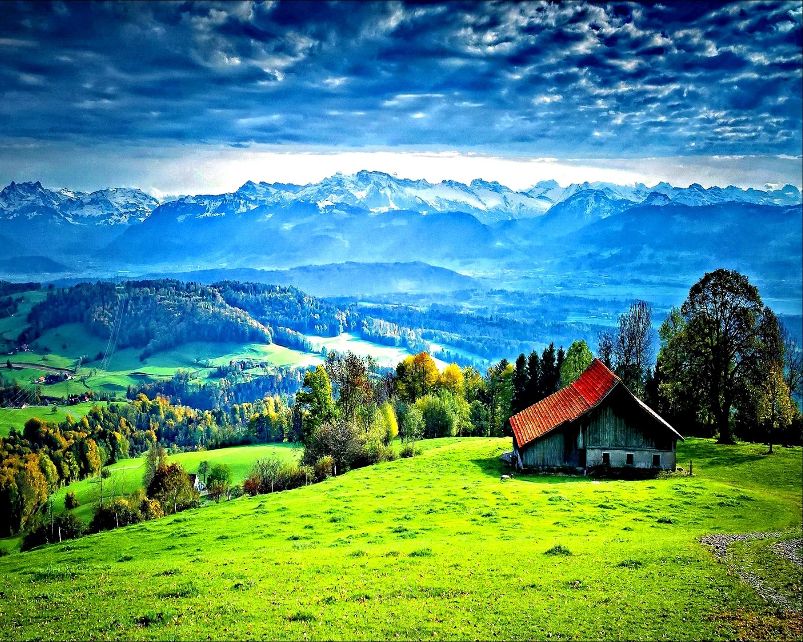 Eine nahaufnahme eines kleinen hauses auf einem feld mit bergen im hintergrund (gras, haus)