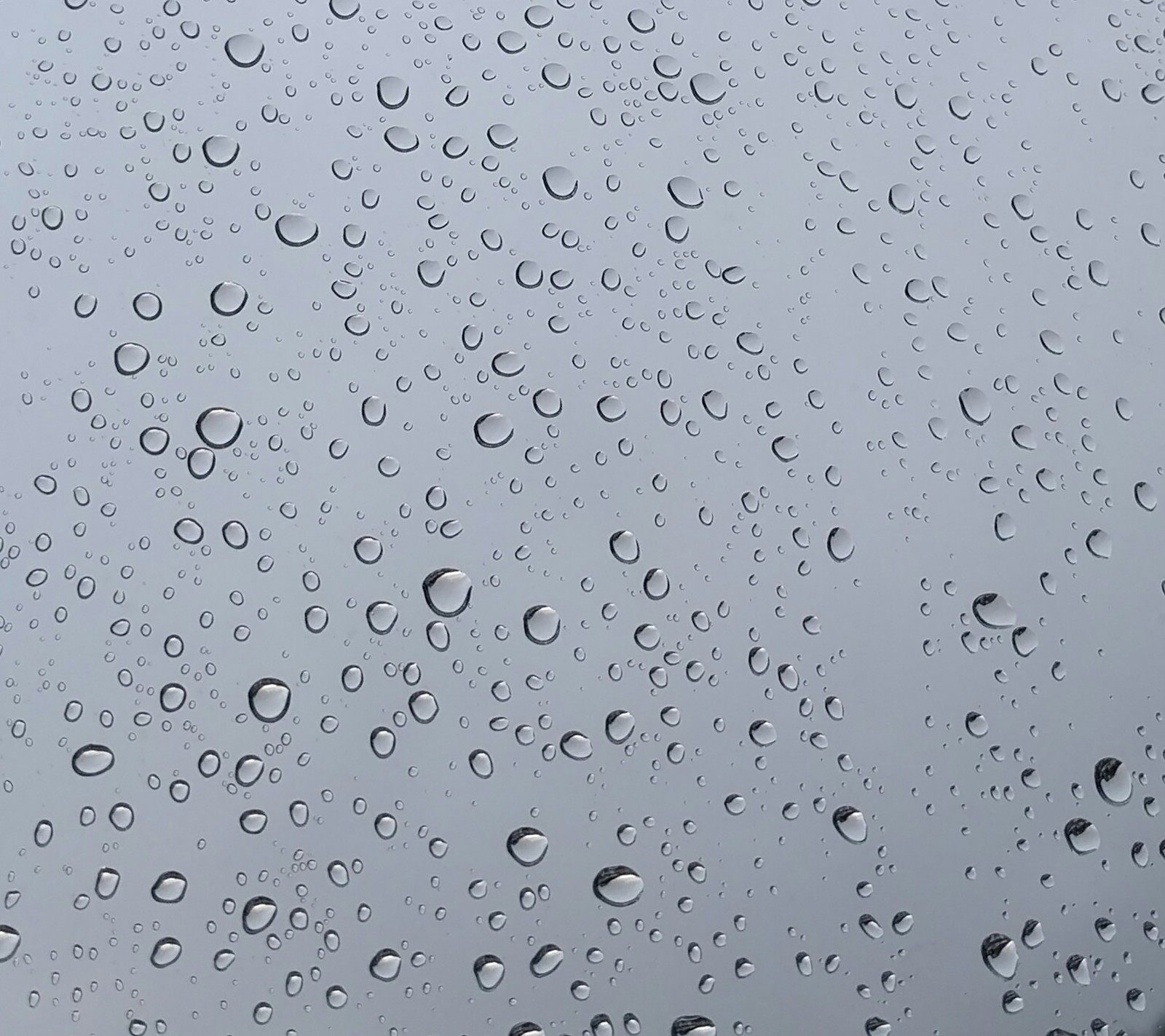 Un primer plano de una ventana con gotas de lluvia sobre ella (gota, gotas, gris, lluvia, lluvioso)