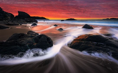 Sérénité du coucher de soleil à la plage de Marshall : Ciel orange vibrant sur les rochers de l'océan