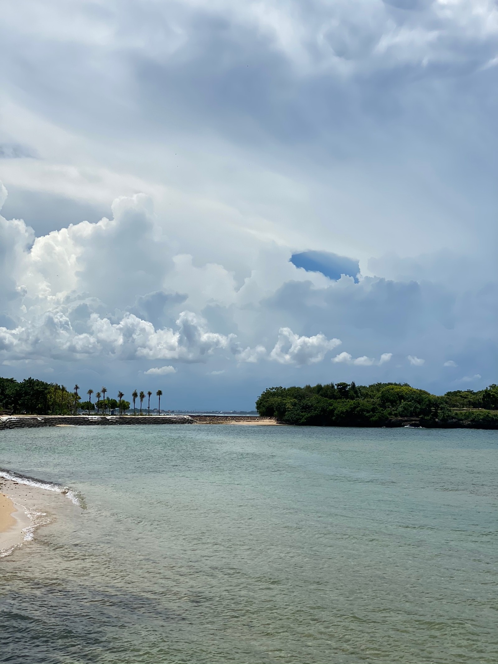 Il y a une plage avec un bateau dans l'eau et un ciel nuageux (ressources en eau, eau, plan deau, journée, nuage)