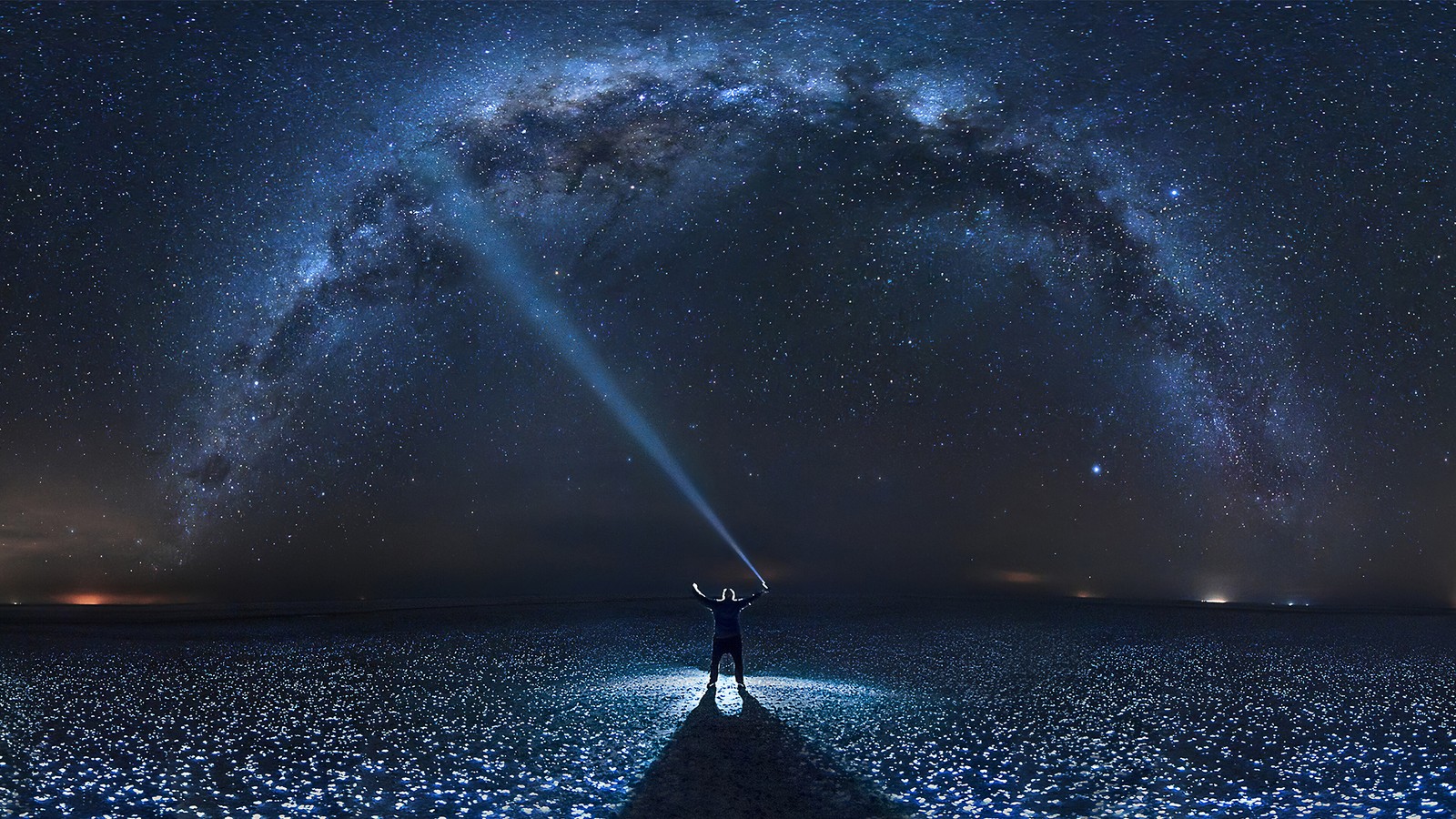 Uma pessoa em pé no meio de um campo com uma luz brilhando sobre ela (estrelas, noite, céu, cenário, homem)