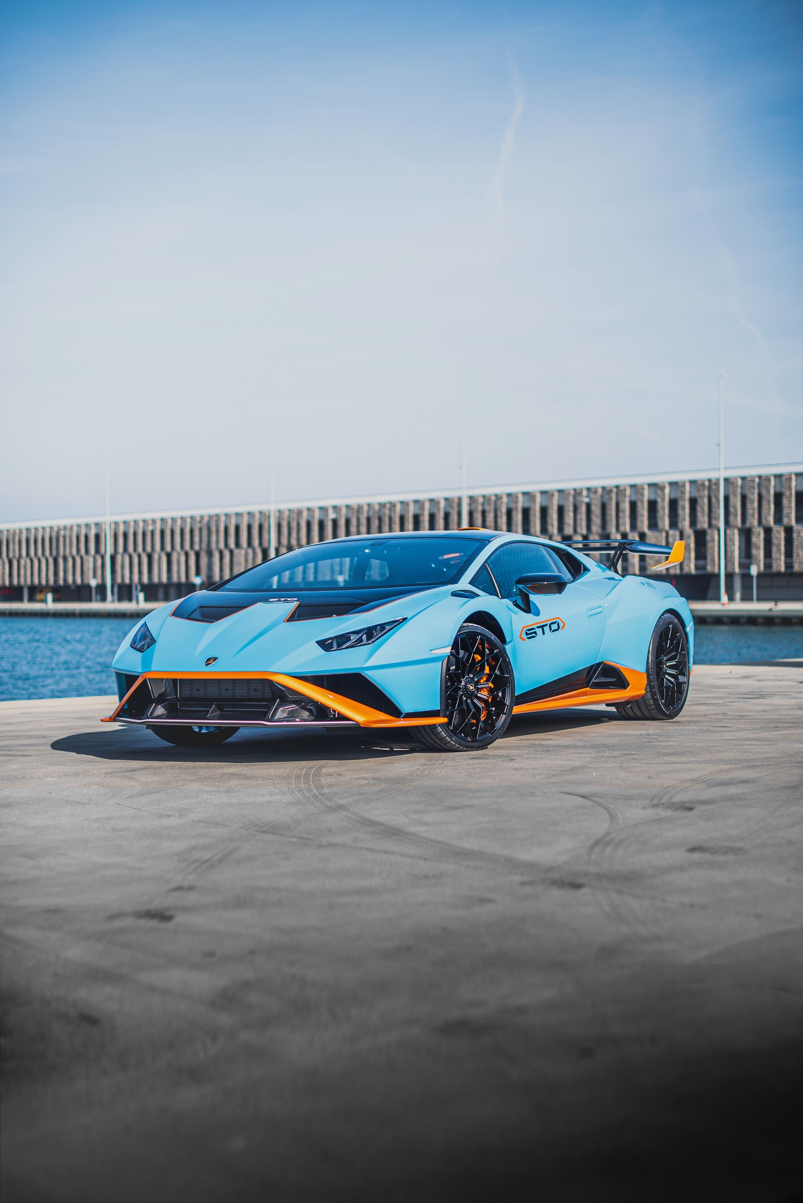 Un primer plano de un coche deportivo azul y naranja estacionado en un aparcamiento (lamborghini huracán sto, coches de lujo, 2021, coches, fondo de pantalla 4k)