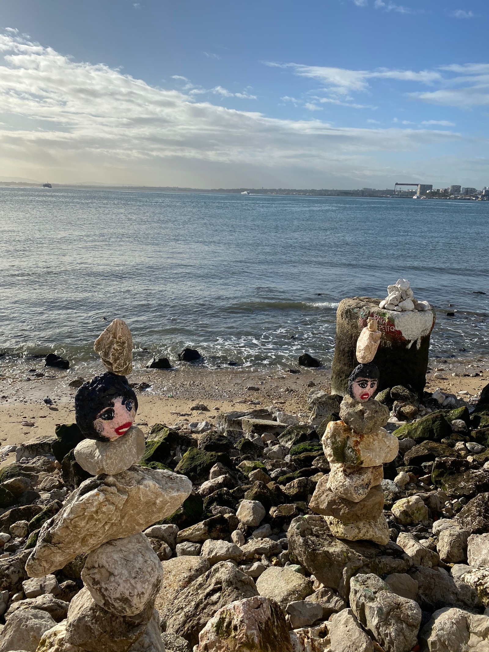 На пляже много сложенных камней с статуей женщины (море, вода, берег, туризм, водоем)