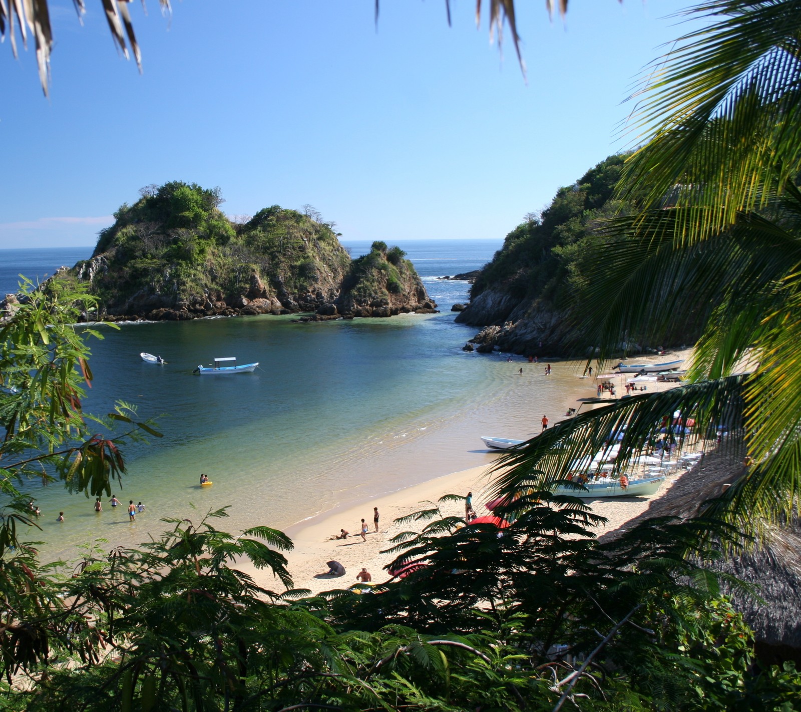 Una playa con un barco y personas en ella (playa, mar, méxico, naturaleza, oaxaca)