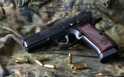 Black handgun with a textured grip resting on camouflage fabric, surrounded by spent cartridges.