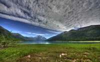 Sereno lago de montaña rodeado de majestuosas montañas y cielos reflectantes