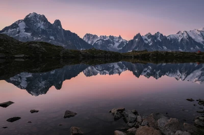 Der Cheserys-See bei Sonnenaufgang, der die majestätischen schneebedeckten Berge der Französischen Alpen spiegelt.