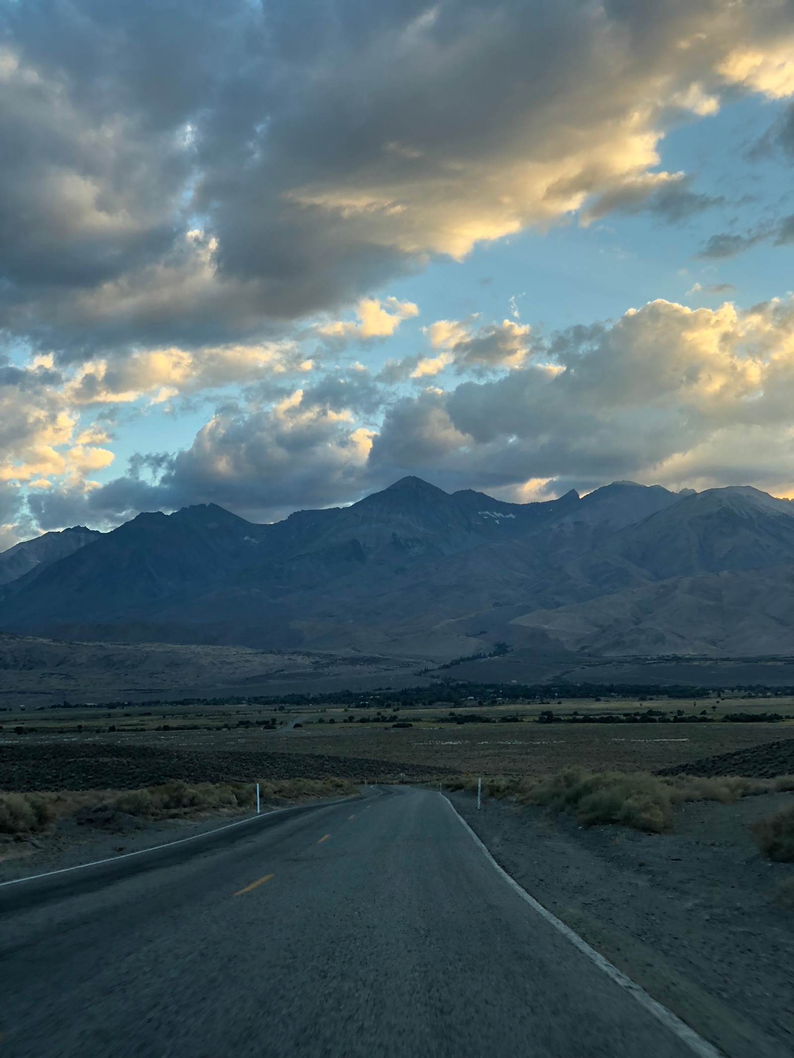 Une route avec des montagnes au loin et des nuages dans le ciel (route, nuage, surface de la route, infrastructure, asphalte)