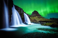 Der Kirkjufell-Berg und Wasserfälle unter dem Nordlicht in der Dämmerungslandschaft Islands.