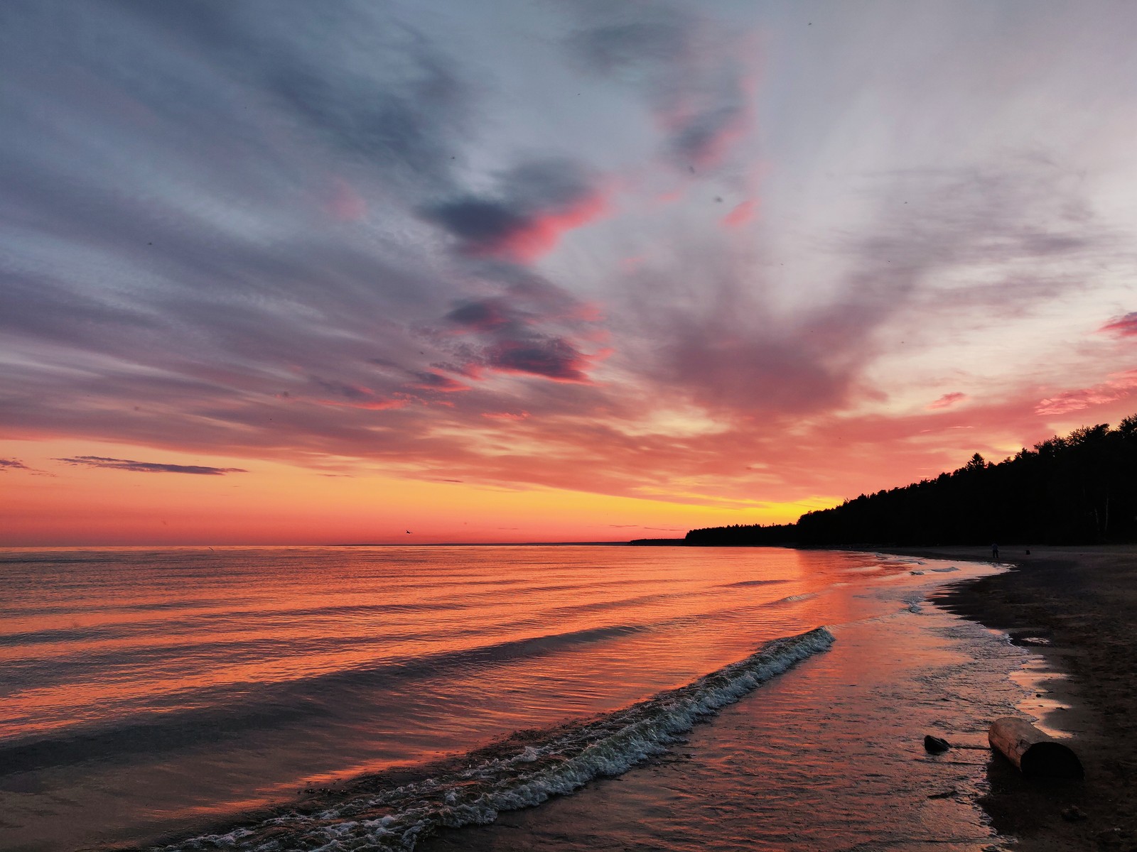 Pôr do sol sobre o oceano com uma praia e um barco na água (corpo de água, resplendor, natureza, horizonte, mar)