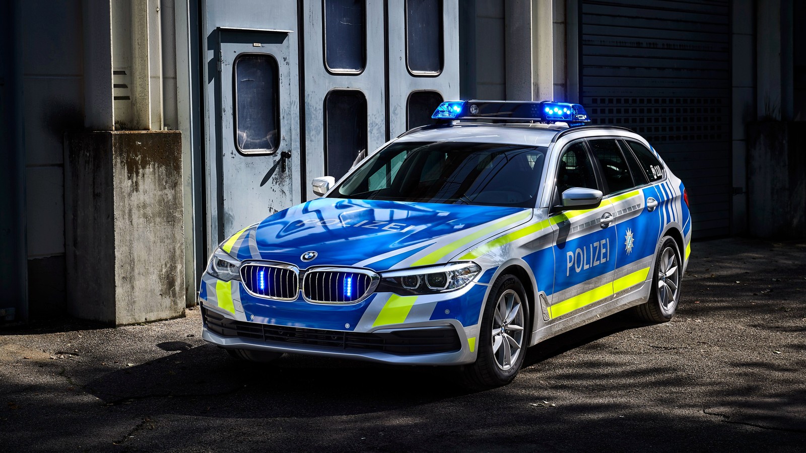 Un primer plano de un coche de policía estacionado frente a un edificio (auto de policía, coches, neumático, rueda, azul)