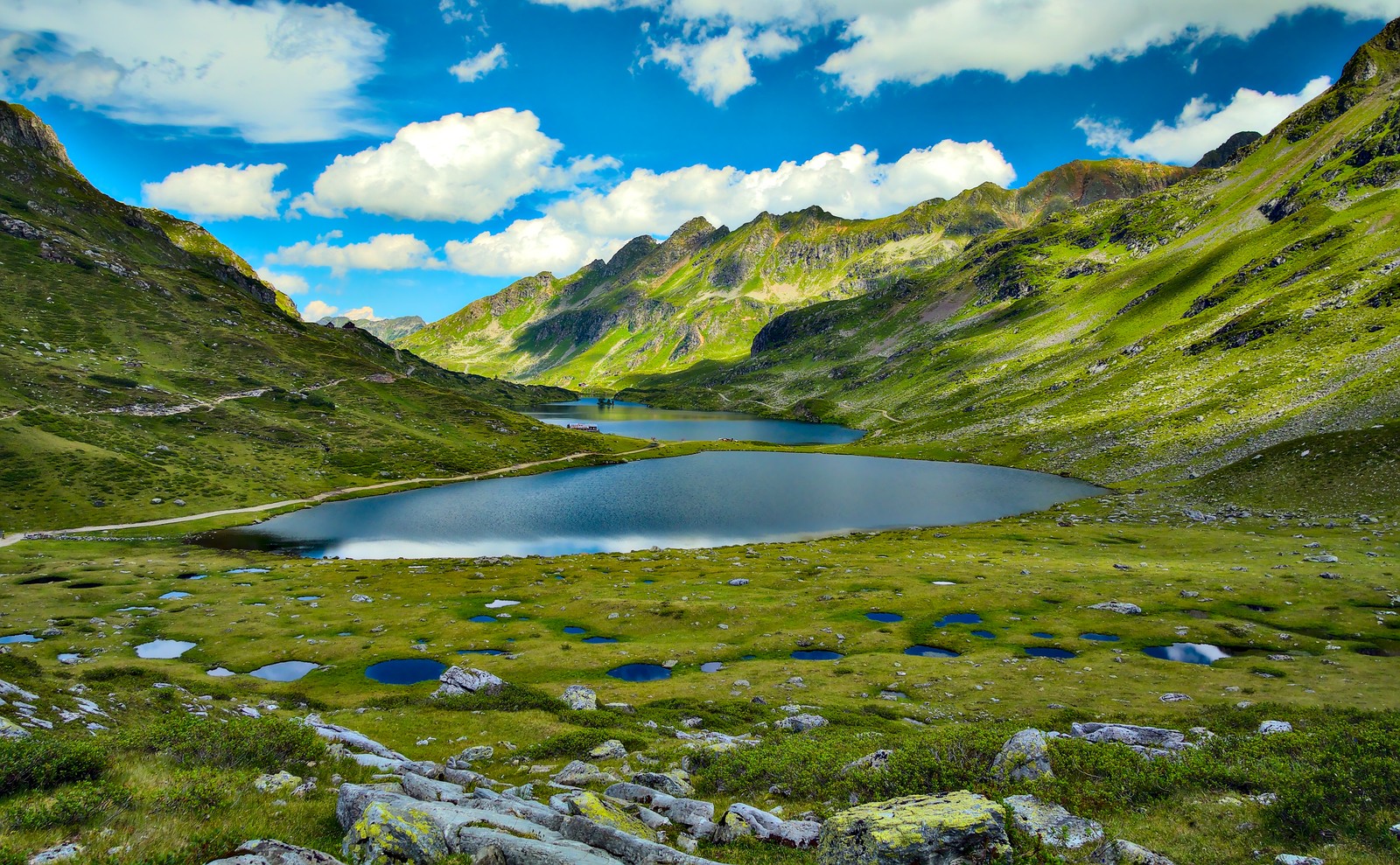 Uma vista de um lago no meio de uma cadeia de montanhas (montanha, natureza, nuvem, água, recursos hídricos)