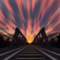 Atardecer vibrante sobre las vías del tren con cielo dramático