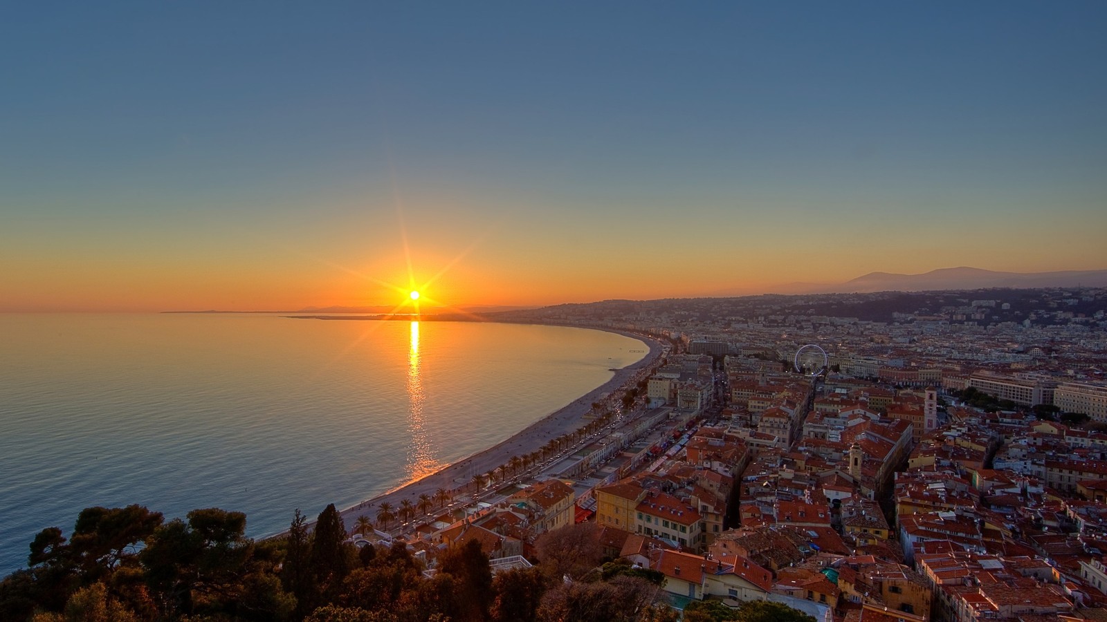 Vista de una ciudad con una playa y un atardecer de fondo (horizonte, atardecer, mar, amanecer, mañana)