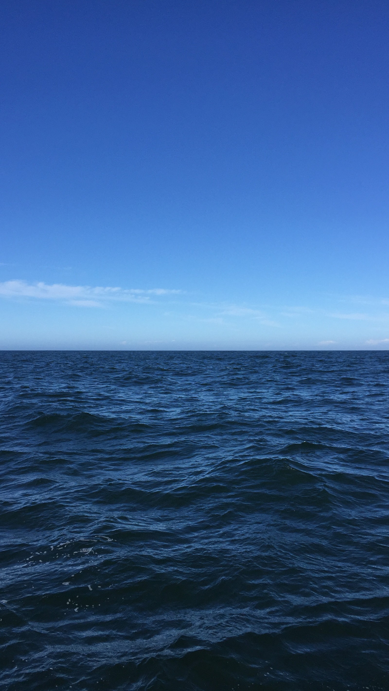 Ein großer gewässer mit einem boot in der ferne. (blau, tief, last frontier, ozean, himmel)