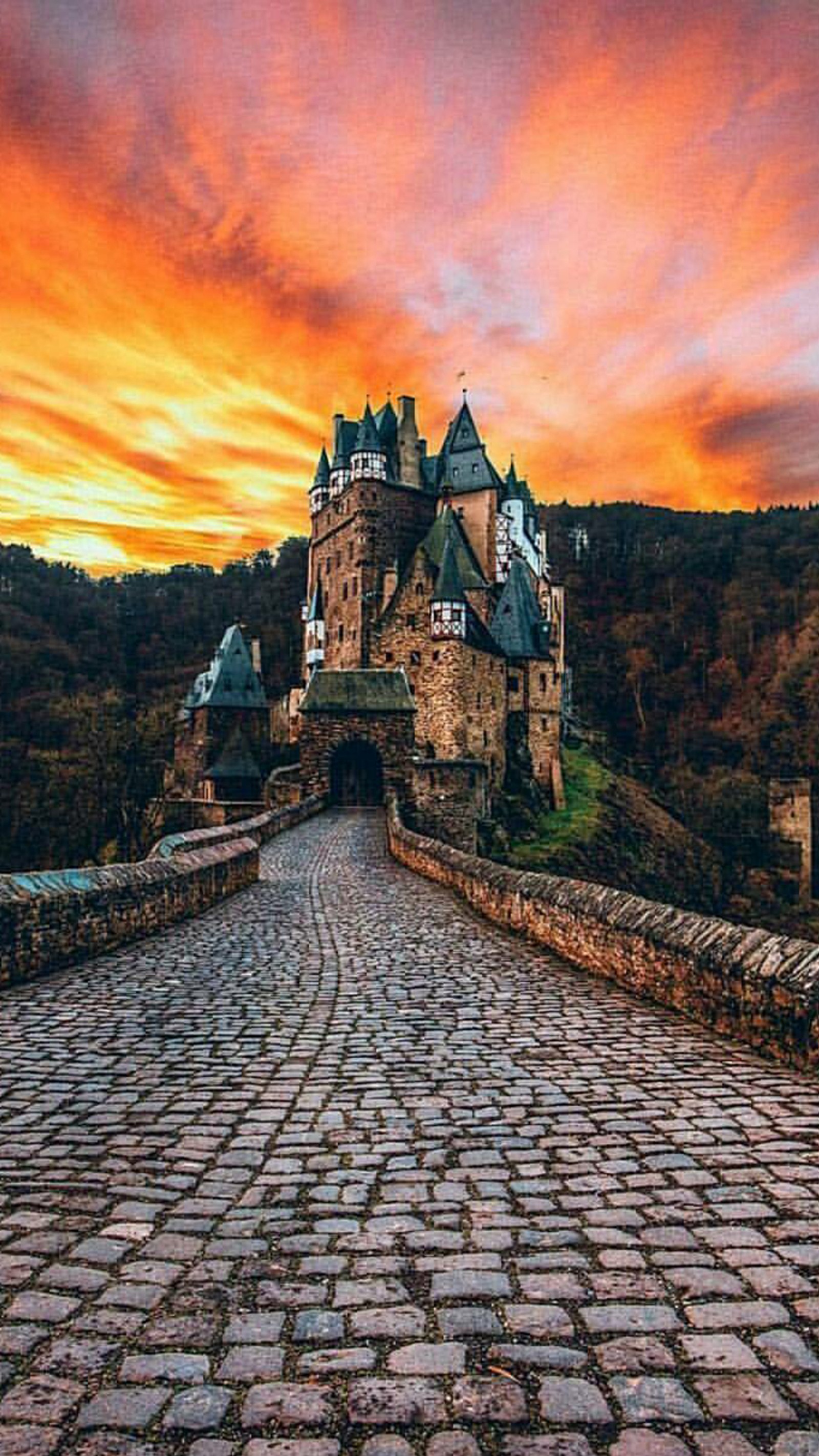 Vue aérienne d'un château avec un pont et un coucher de soleil (château, paysage)