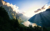 Valle soleado con vistas a un lago sereno entre majestuosas montañas