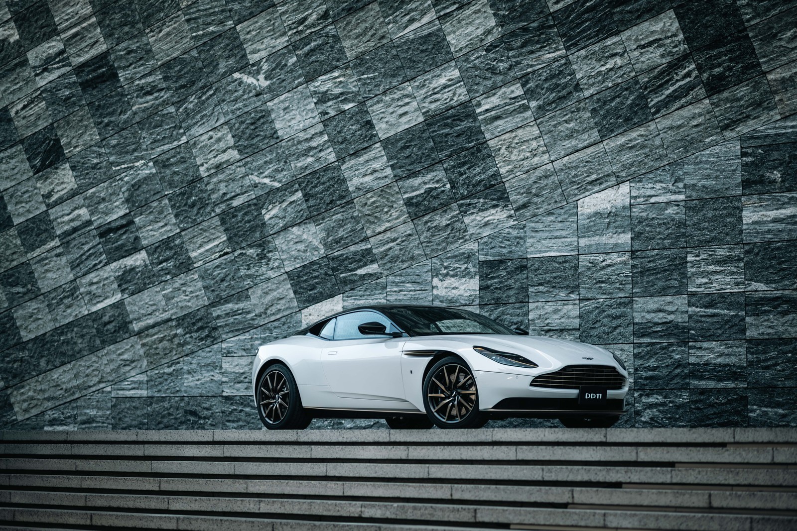 Um carro esportivo branco estacionado em uma escada de pedra ao lado de uma parede (aston martin db11 v8, 2022, 5k, 8k, carros)