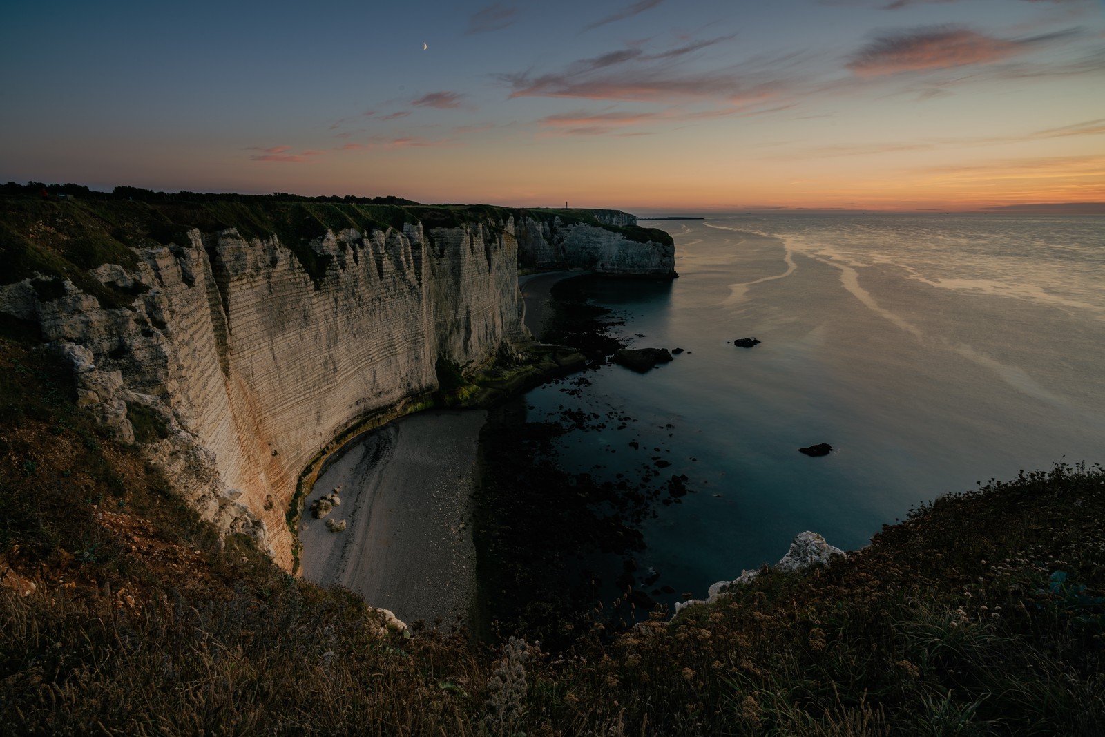 A view of a cliff with a body of water and a beach (water, cloud, water resources, natural landscape, body of water)