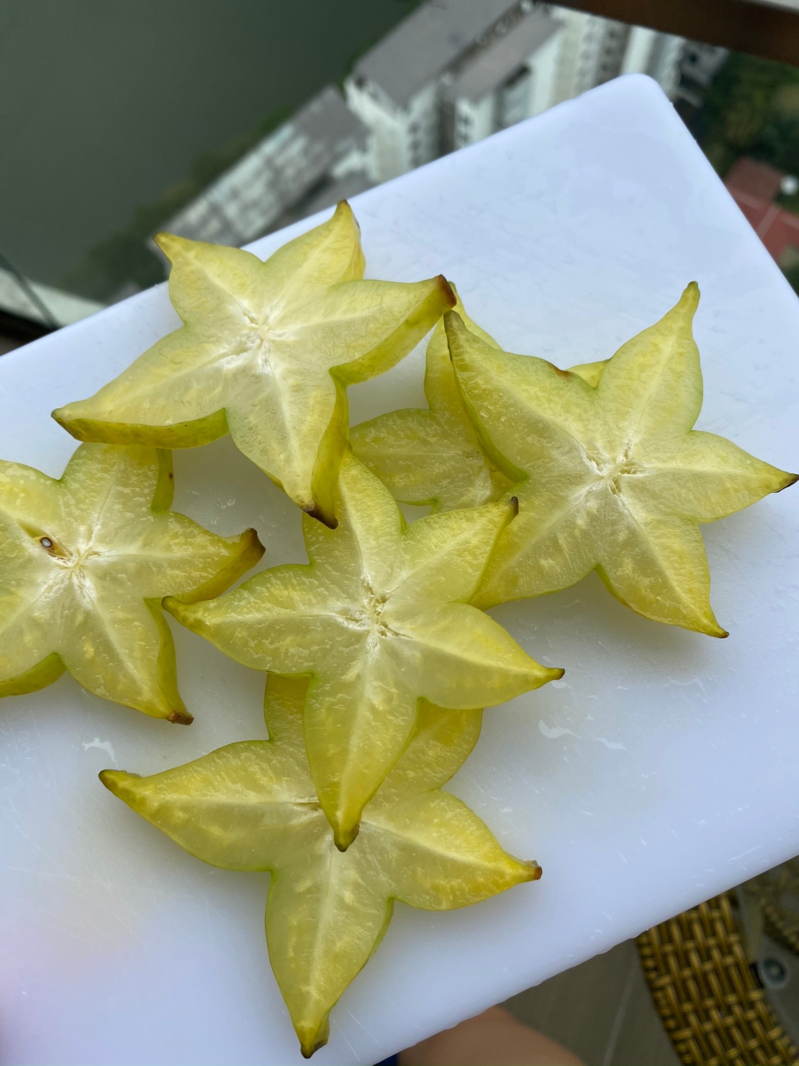 Auf einem schneidebrett auf einem tisch liegen fünf sternfrüchte. (biologie, wissenschaft, gelb, rezept, blütenblatt)