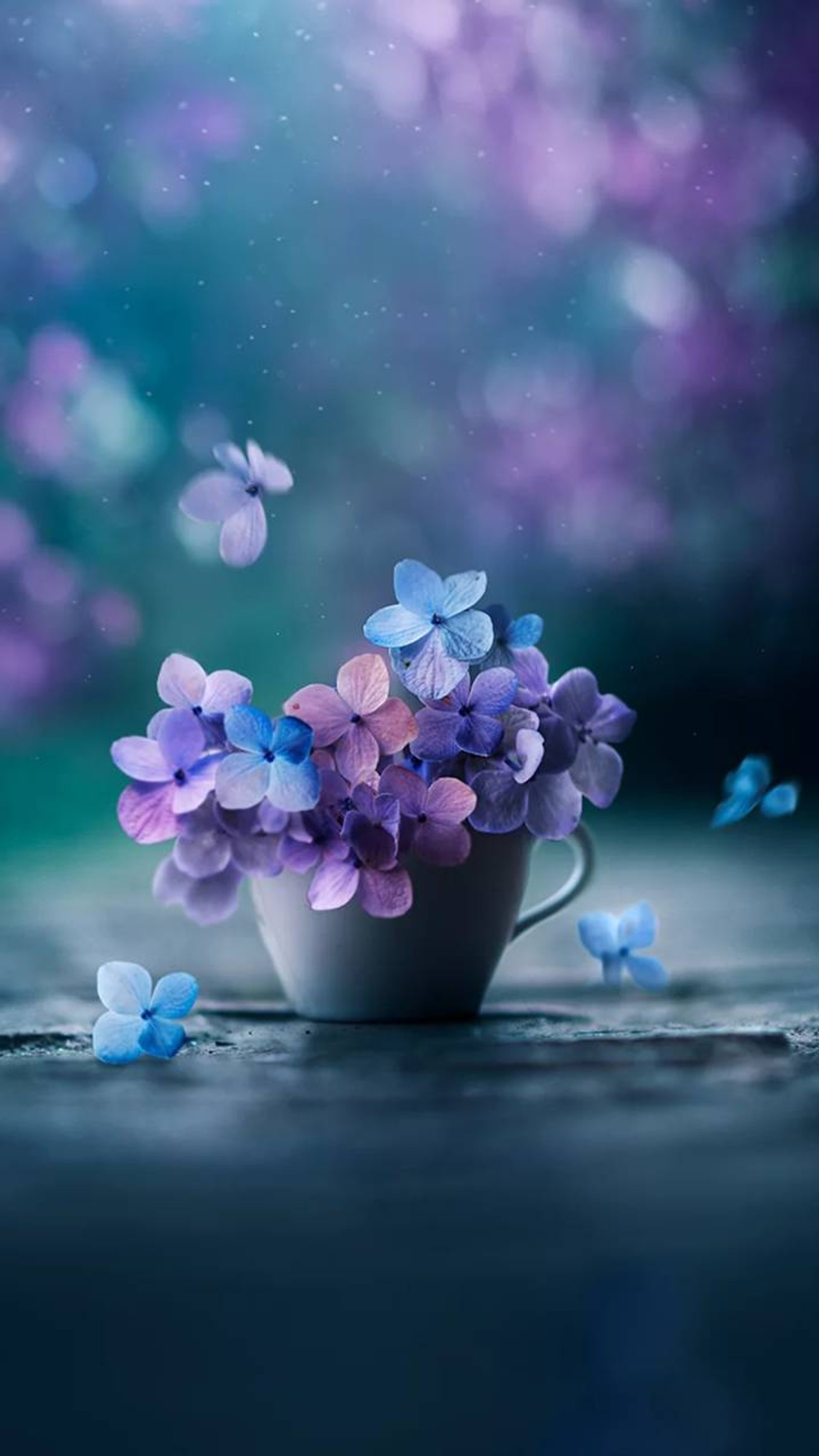 Des fleurs violettes et bleues dans une tasse avec des papillons volant autour (fleur, fleurs)