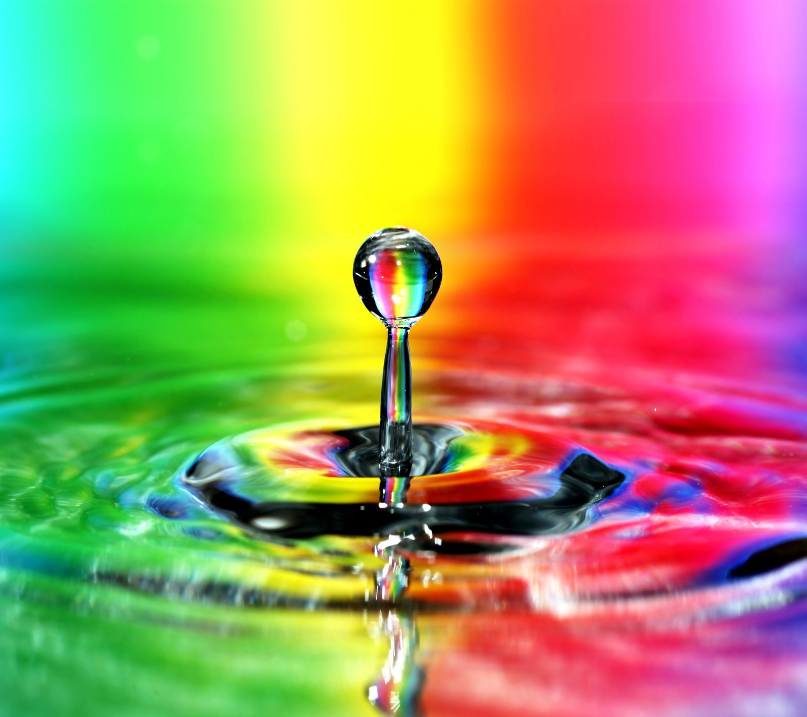 Eine nahaufnahme eines wassertropfens mit einem regenbogen-hintergrund (bunt, tropfen, regenbogen, spritzer, wasser)