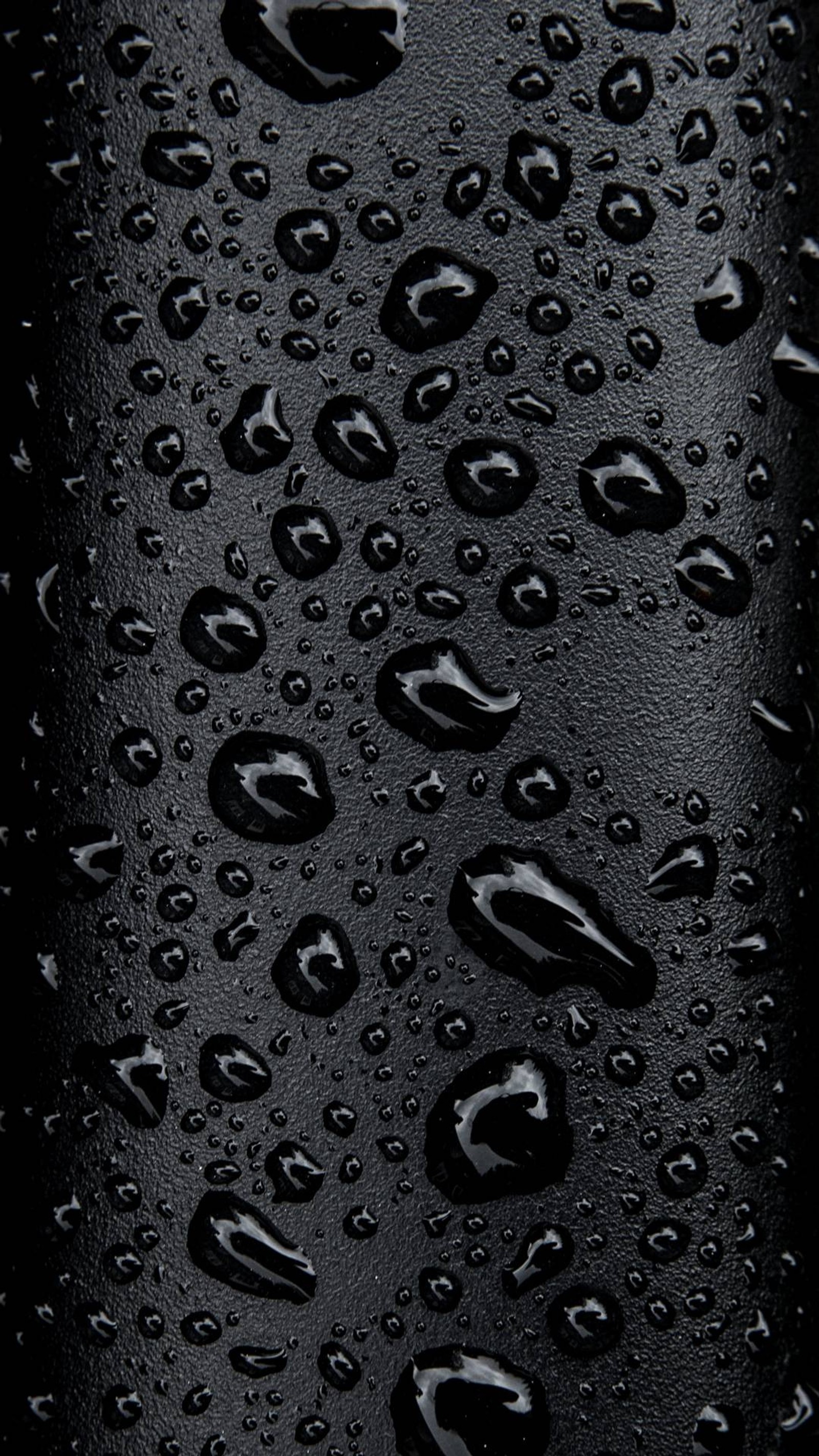 Un primer plano de una botella negra con gotas de agua sobre ella (negro, gotas, lluvia)