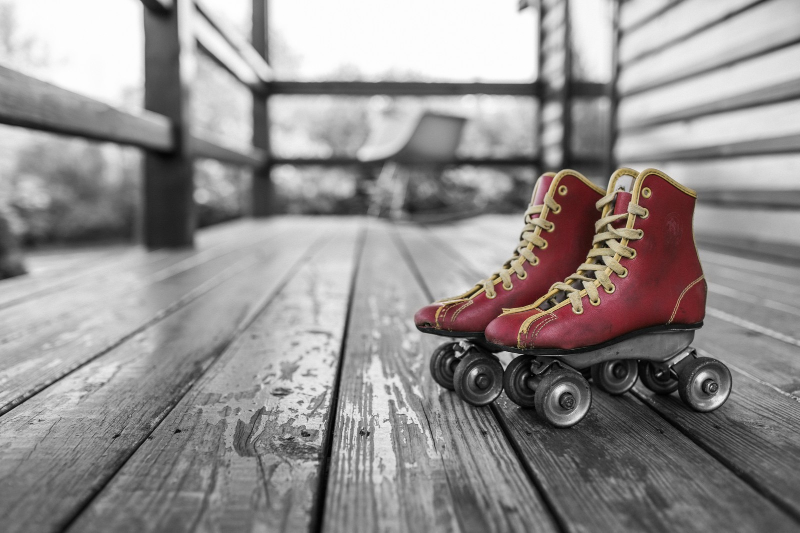 A close up of a pair of red roller skates on a wooden deck (footwear, ice skating, skateboard, shoe, roller skating)