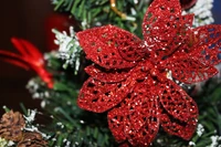 Glittering red poinsettia ornament adorning a festive Christmas tree.