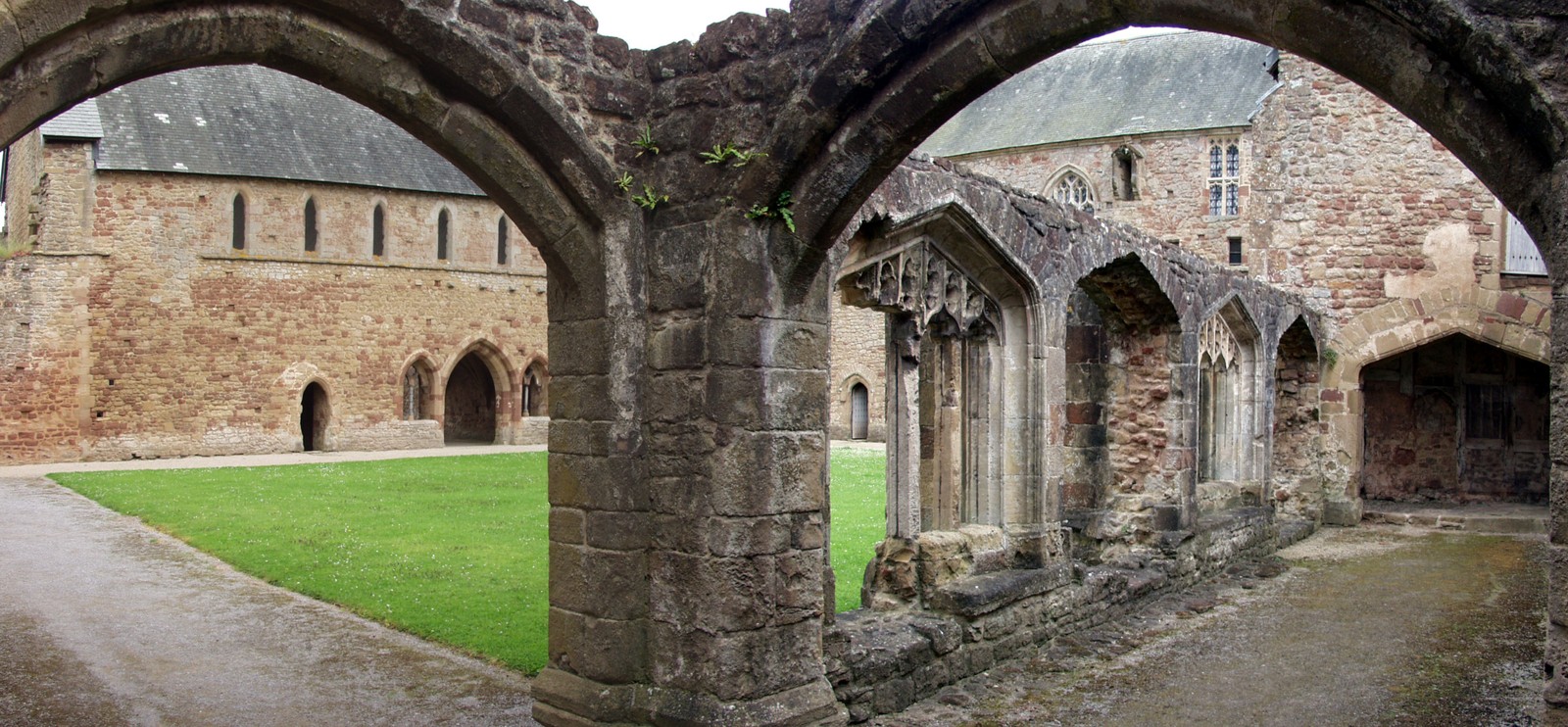 Arafed archways in a stone building with a green lawn (historic site, medieval architecture, history, ruins, middle ages)