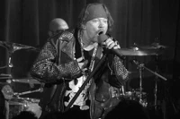 Axl Rose delivering a powerful performance at a rock concert, showcasing his dynamic lead vocals and commanding stage presence.