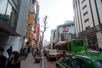 Lebendige Straßenszene in Tokio mit Bussen und Taxis in einem pulsierenden Stadtviertel