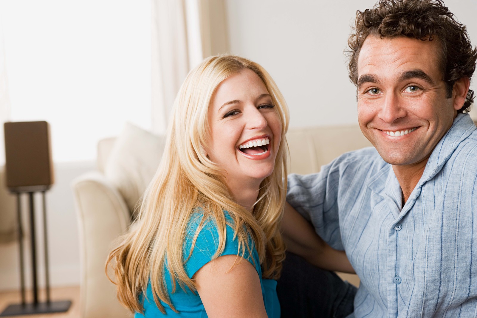 Casal sorridente sentado em um sofá em uma sala de estar (sorriso, risada, diversão, mulher, humano)