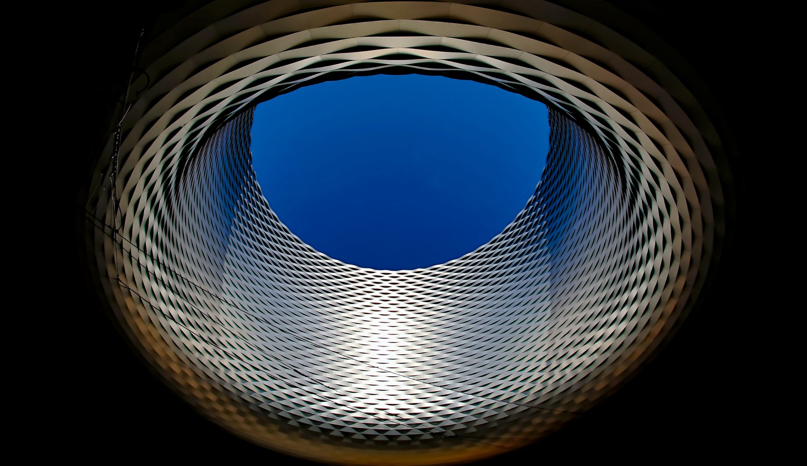 Una vista de una estructura circular con un cielo azul de fondo (centro de exposiciones de basilea, suiza, arquitectura moderna, vista del cielo, fondo oscuro)