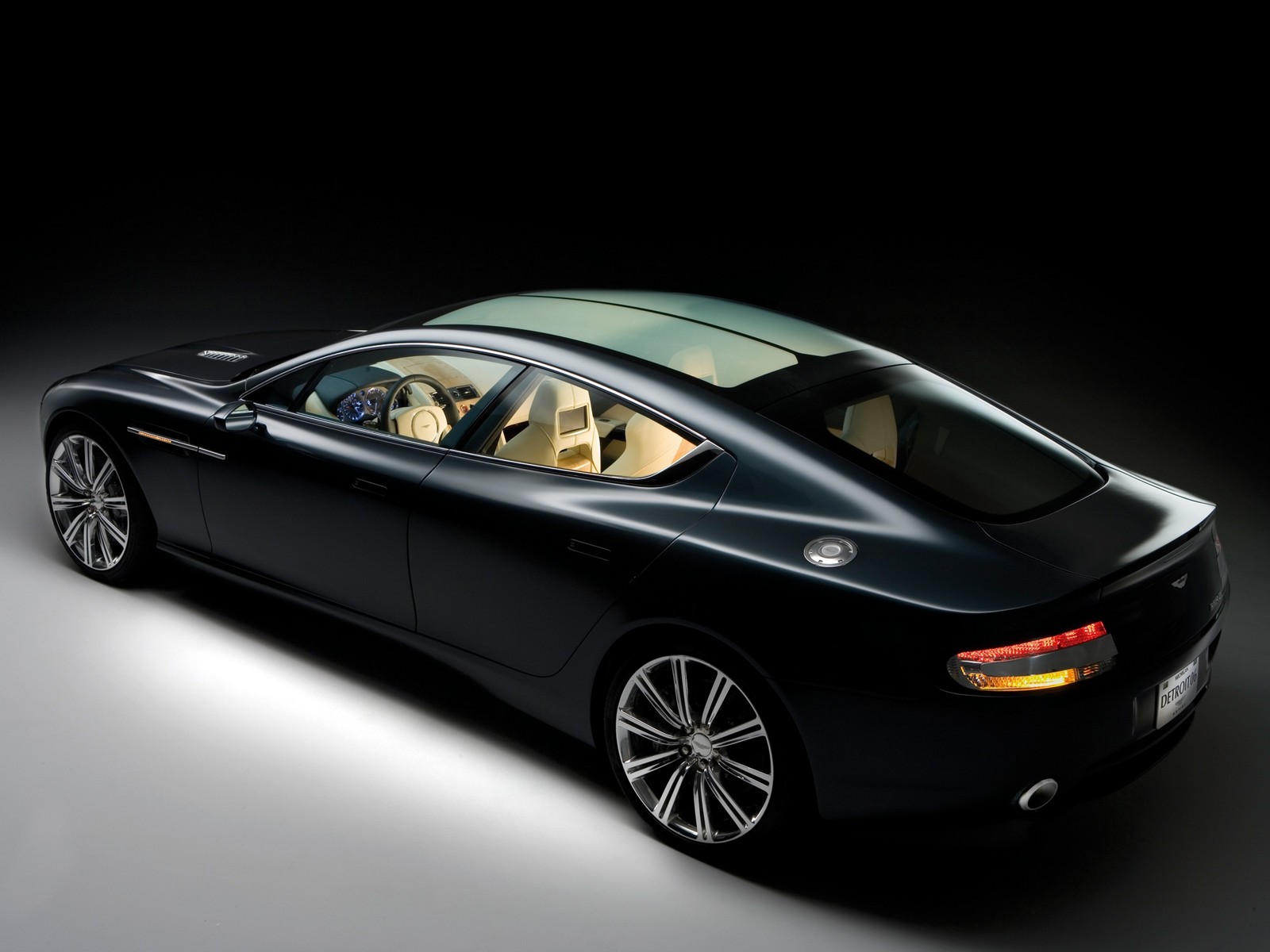 Um carro preto com interior bege mostrado em uma sala escura (carro esportivo, aston martin dbs v12, aston martin db9, aston martin vantage)