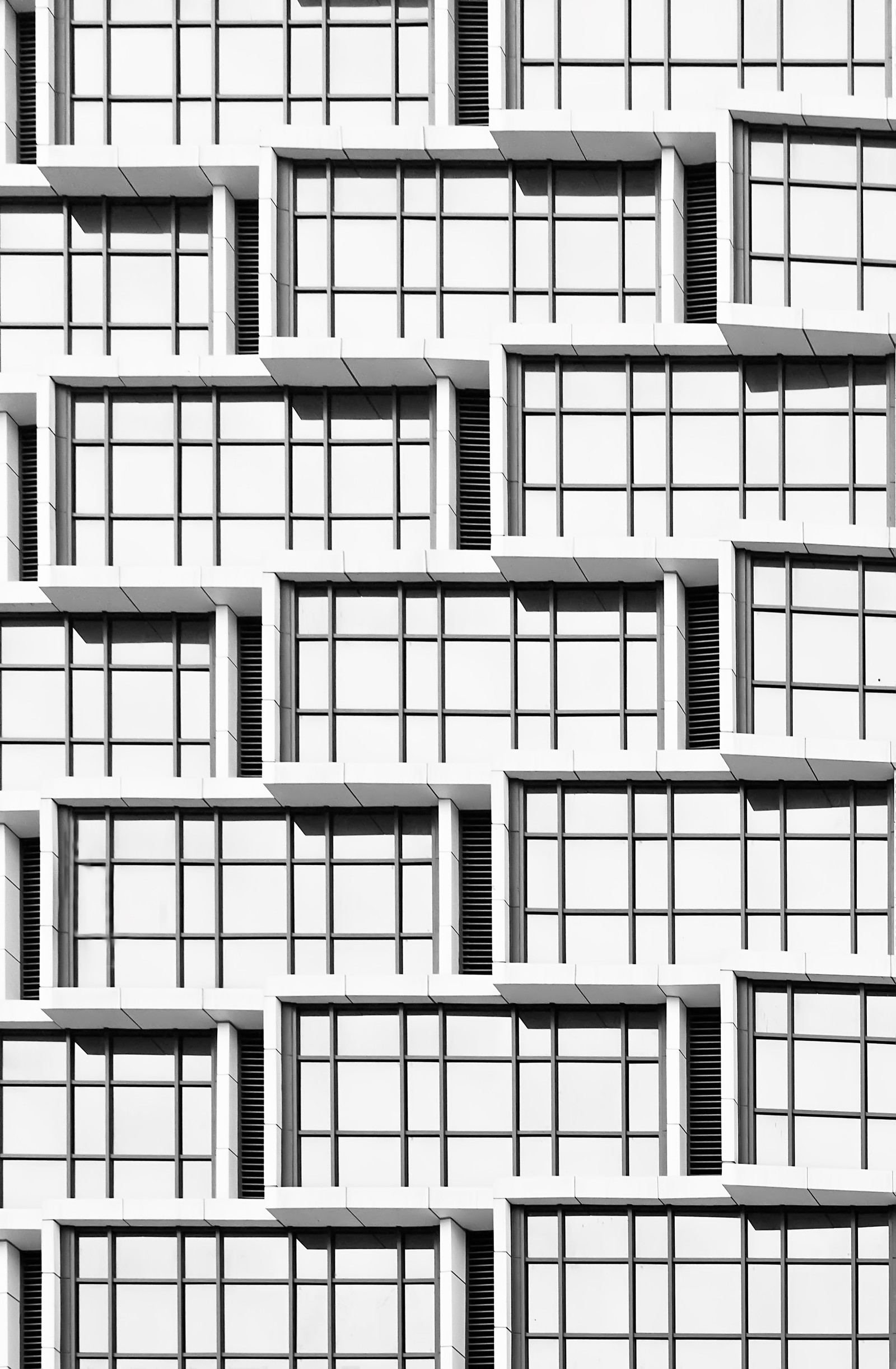 A black and white photo of a building with multiple windows (architecture, black and white, design, line, monochrome)