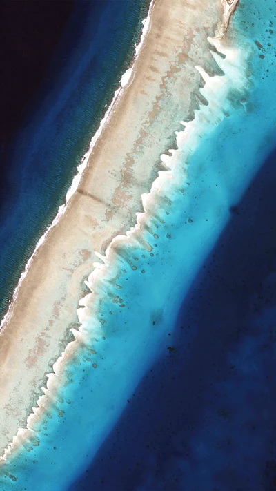 Luftaufnahme einer sandigen Küste, die auf lebhaftes blaues Wasser trifft.