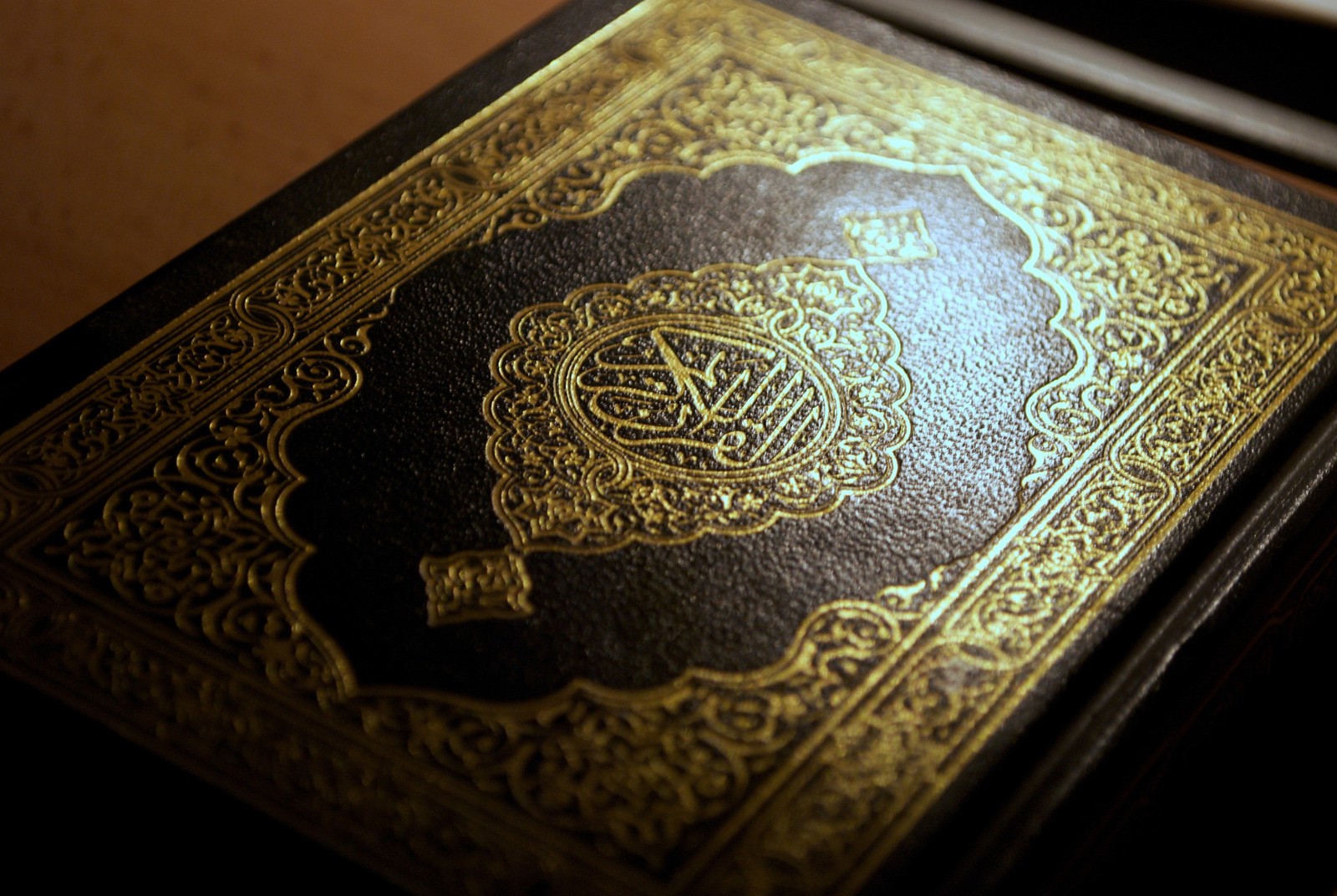 Um close-up de um livro com uma capa dourada em uma mesa. (alá, allah, livro, hd, islão)