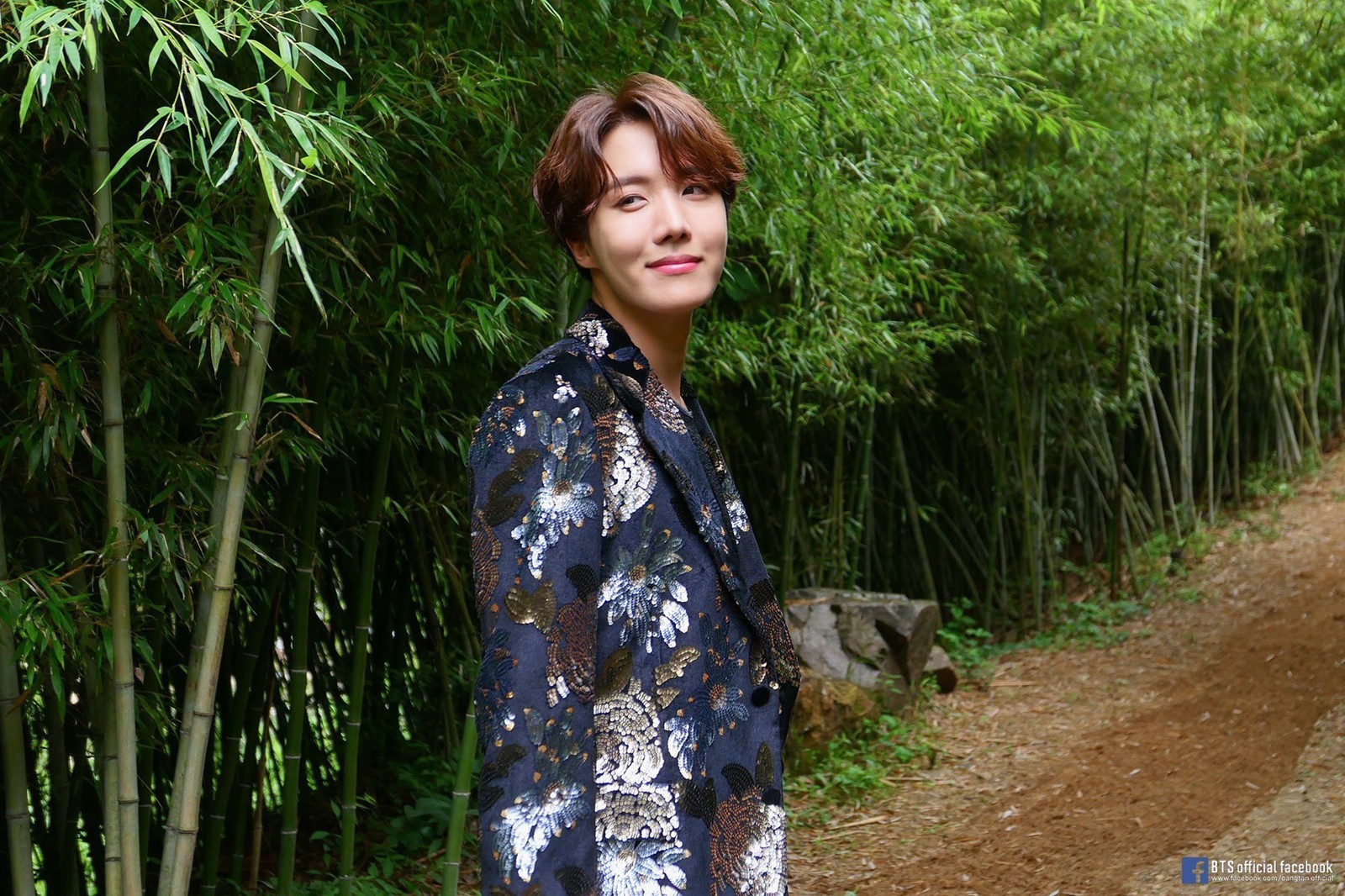 Un homme flou en veste bleue se tenant devant une forêt de bambous (bts, hobi, j hope, jhope)