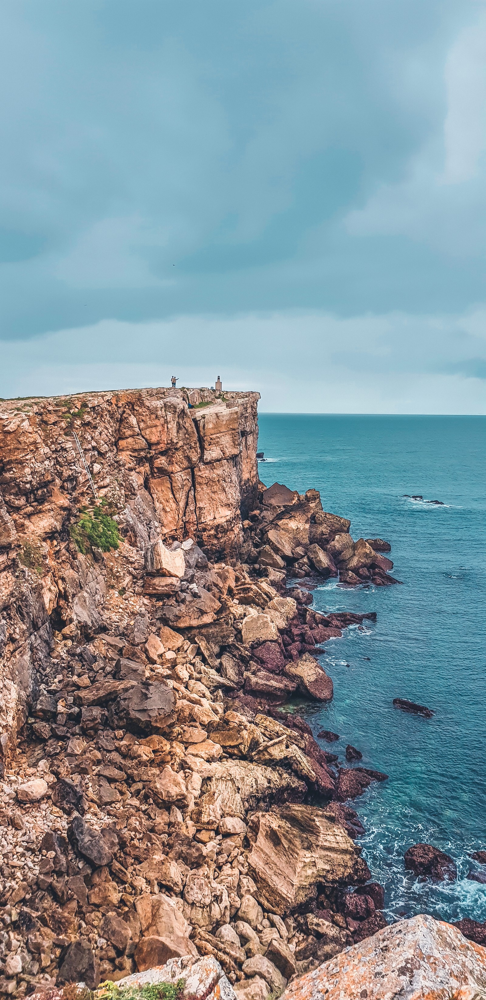 Ein mann steht auf einer klippe und blickt auf den ozean (natur, ozean, meer, himmel, wasser)