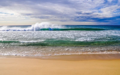 Olas rompiendo en una serena playa australiana bajo un cielo nublado