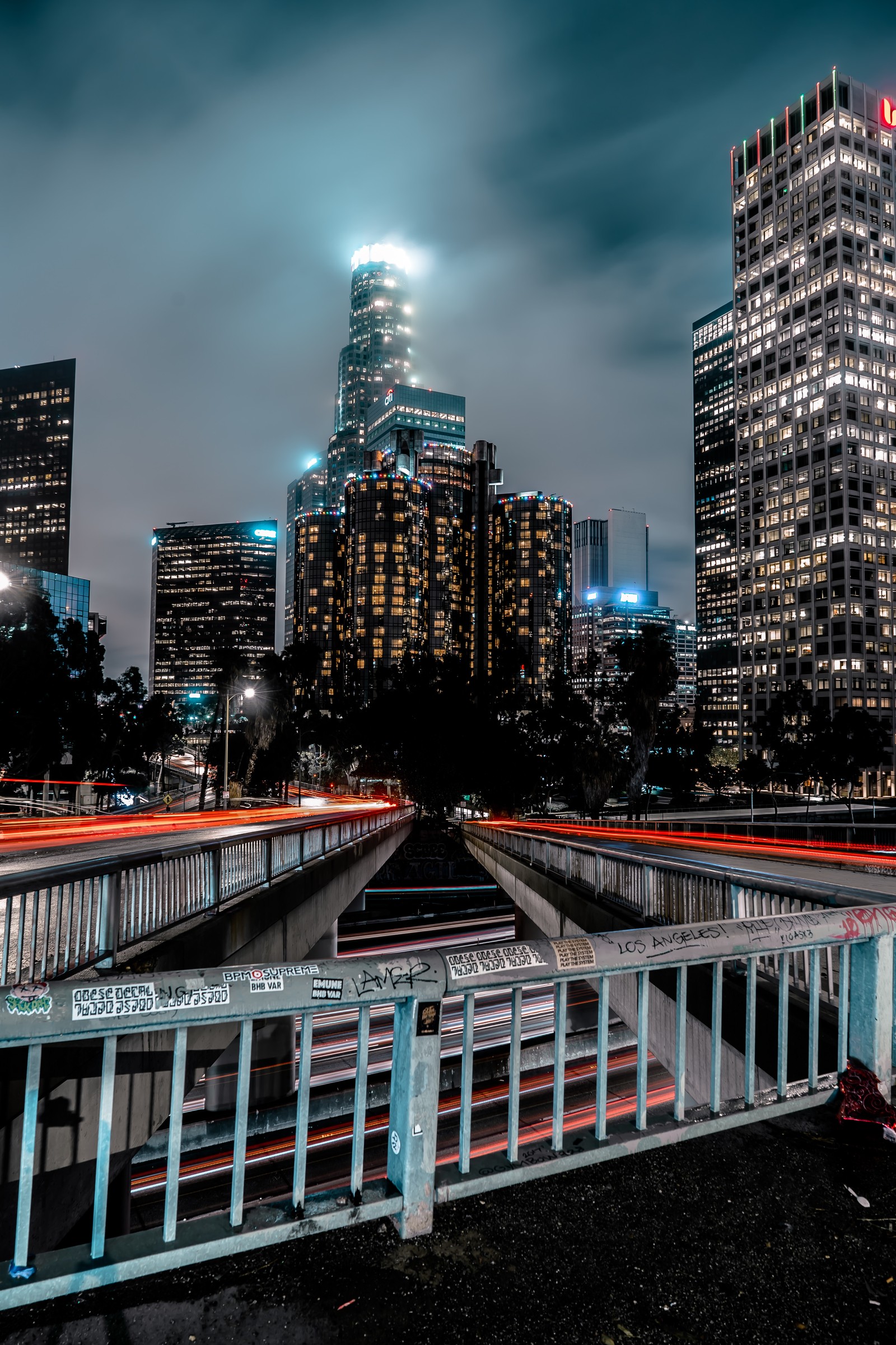 Vista noturna de uma cidade com uma ponte e um carro passando por ela (arquitetura, paisagem urbana, área urbana, metrópole, cidade)