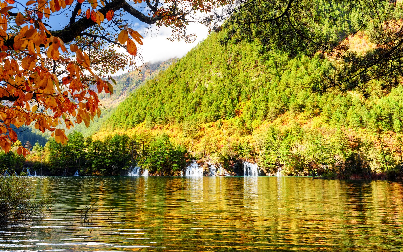 Vista de um lago com uma cachoeira no meio (natureza, corpo de água, reflexo, árvore, vegetação)