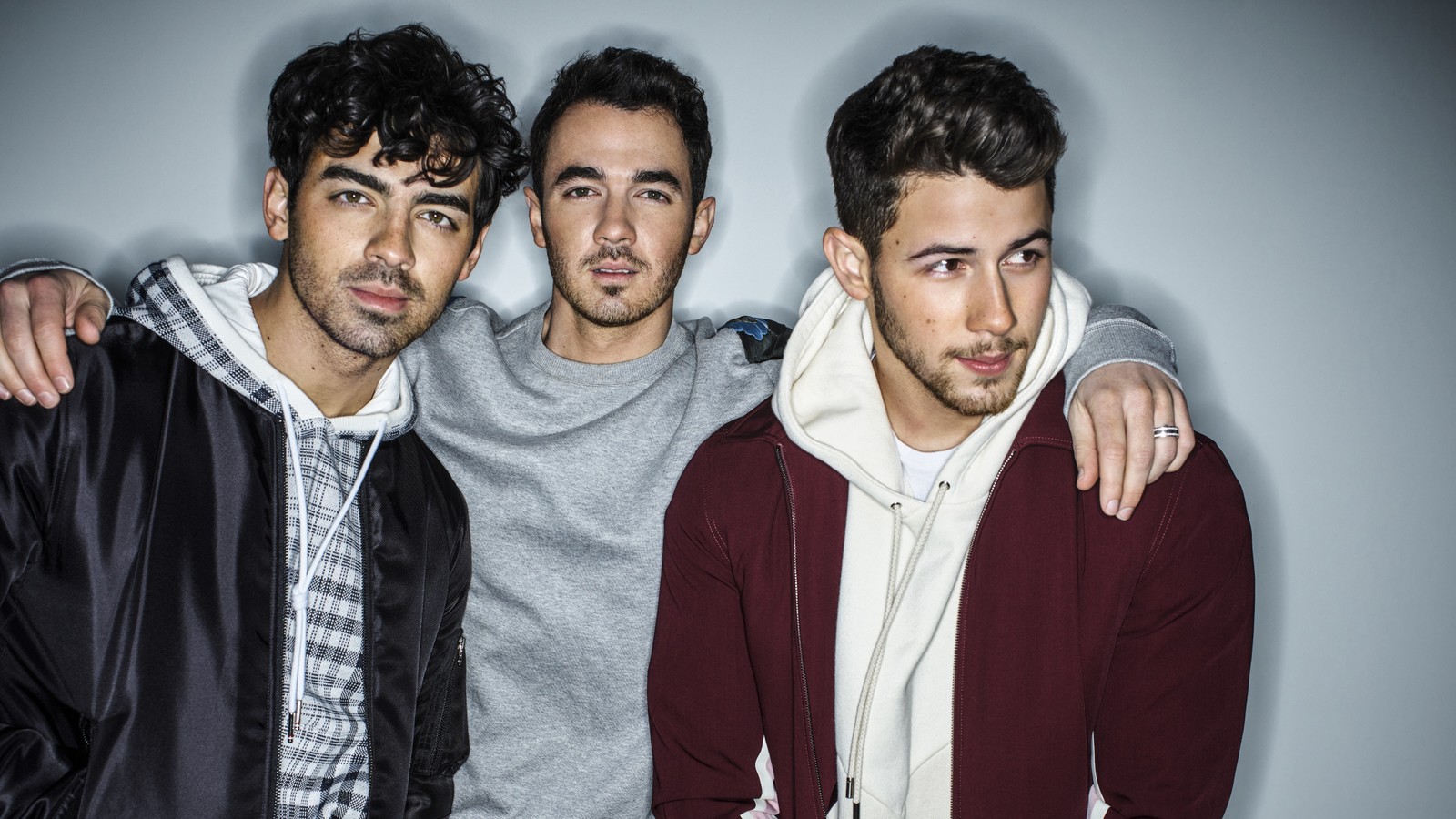 Tres hombres en chaquetas y sudaderas posando para una foto (grupo social, juventud, genial, diversión, amistad)